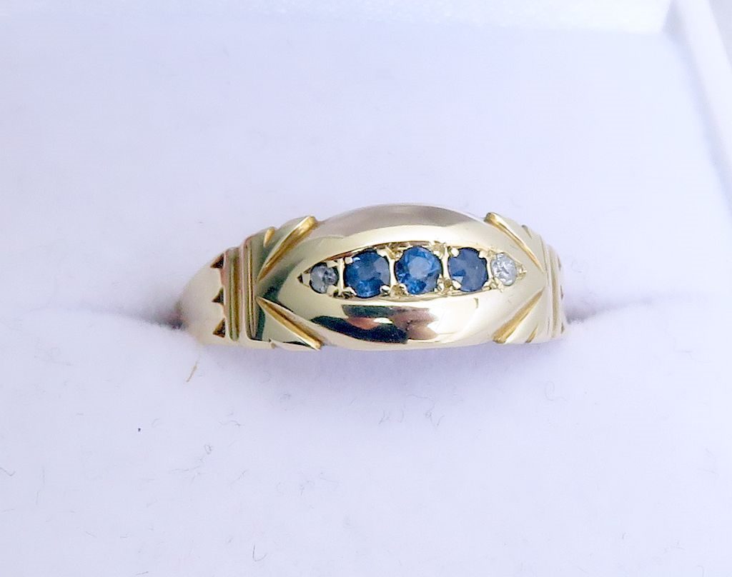 1897 Victorian sapphire and diamond navette ring showing three blue sapphires and two old-cut diamonds in domed gold setting