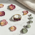 1880s antique gold garnet engagement ring with three cabochon stones, styled on marble with dried rose petals and eucalyptus